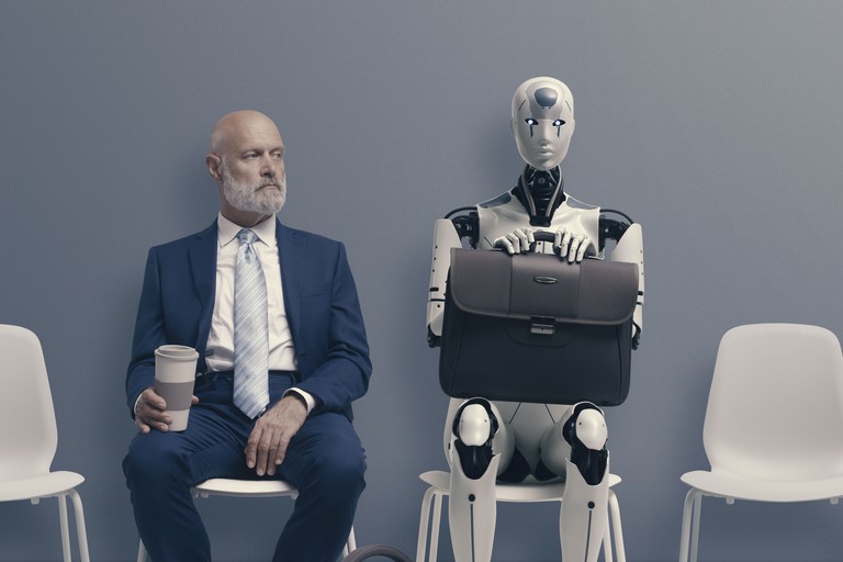 Man sitzt neben Roboter und wartet auf Vorstellungsgespräch.