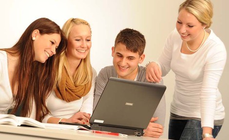Gruppe Menschen guckt auf einen Laptop.