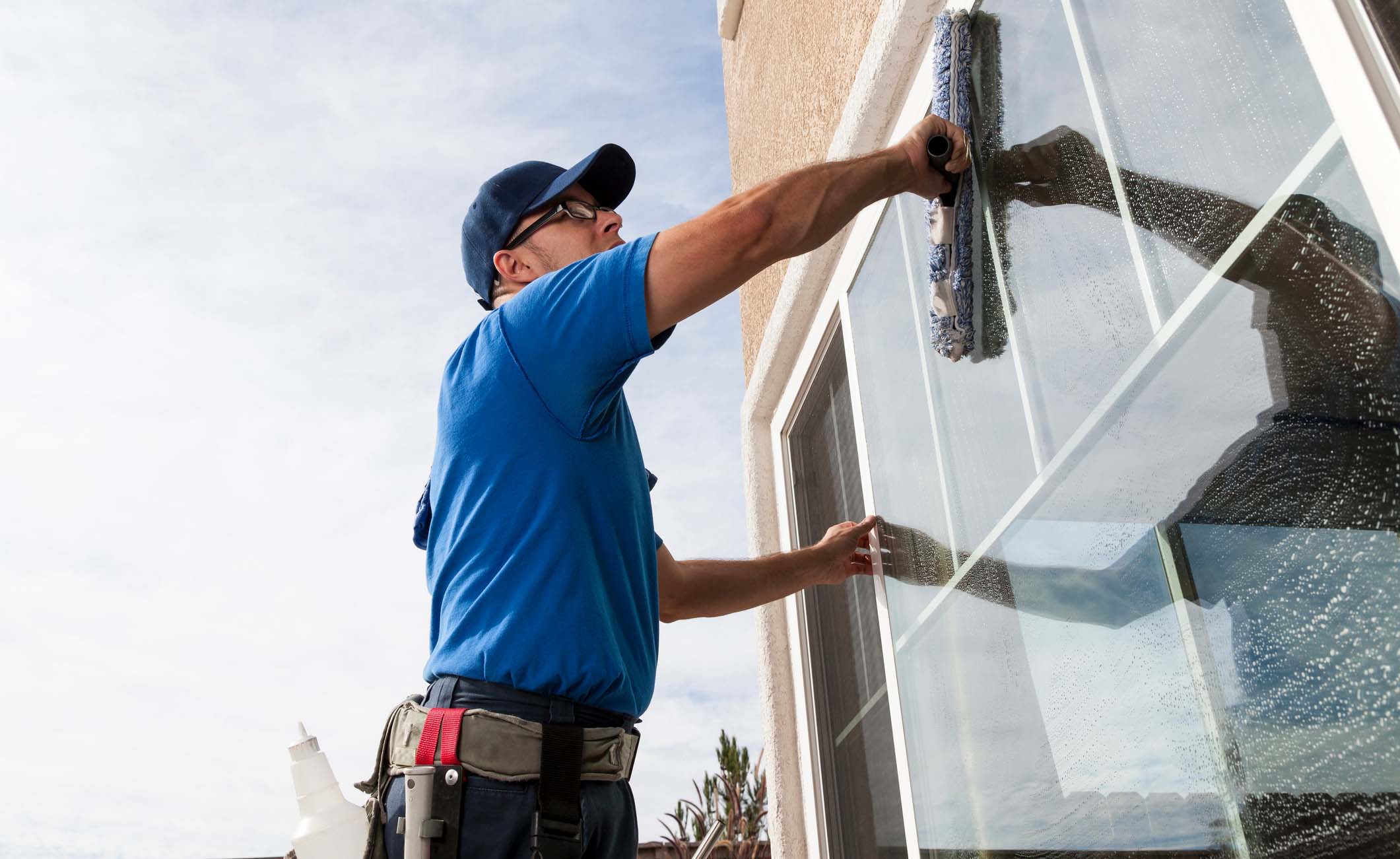 Ein Mann, der professionell die Fenster eines Gebäudes von außen putzt