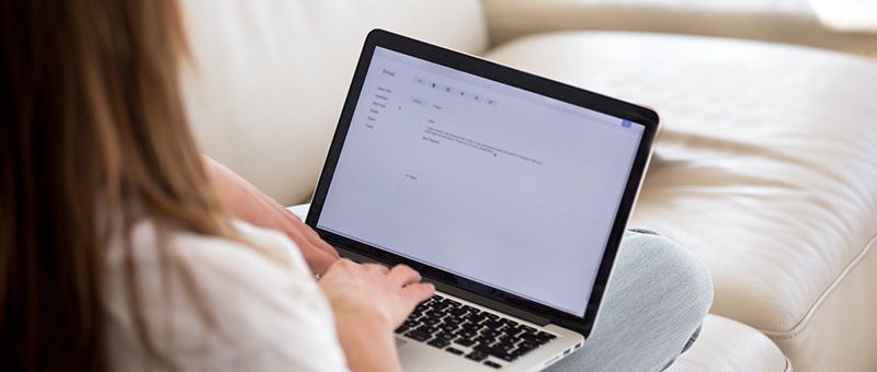 Junge Frau verfasst am Laptop eine E-Mail-Bewerbung.
