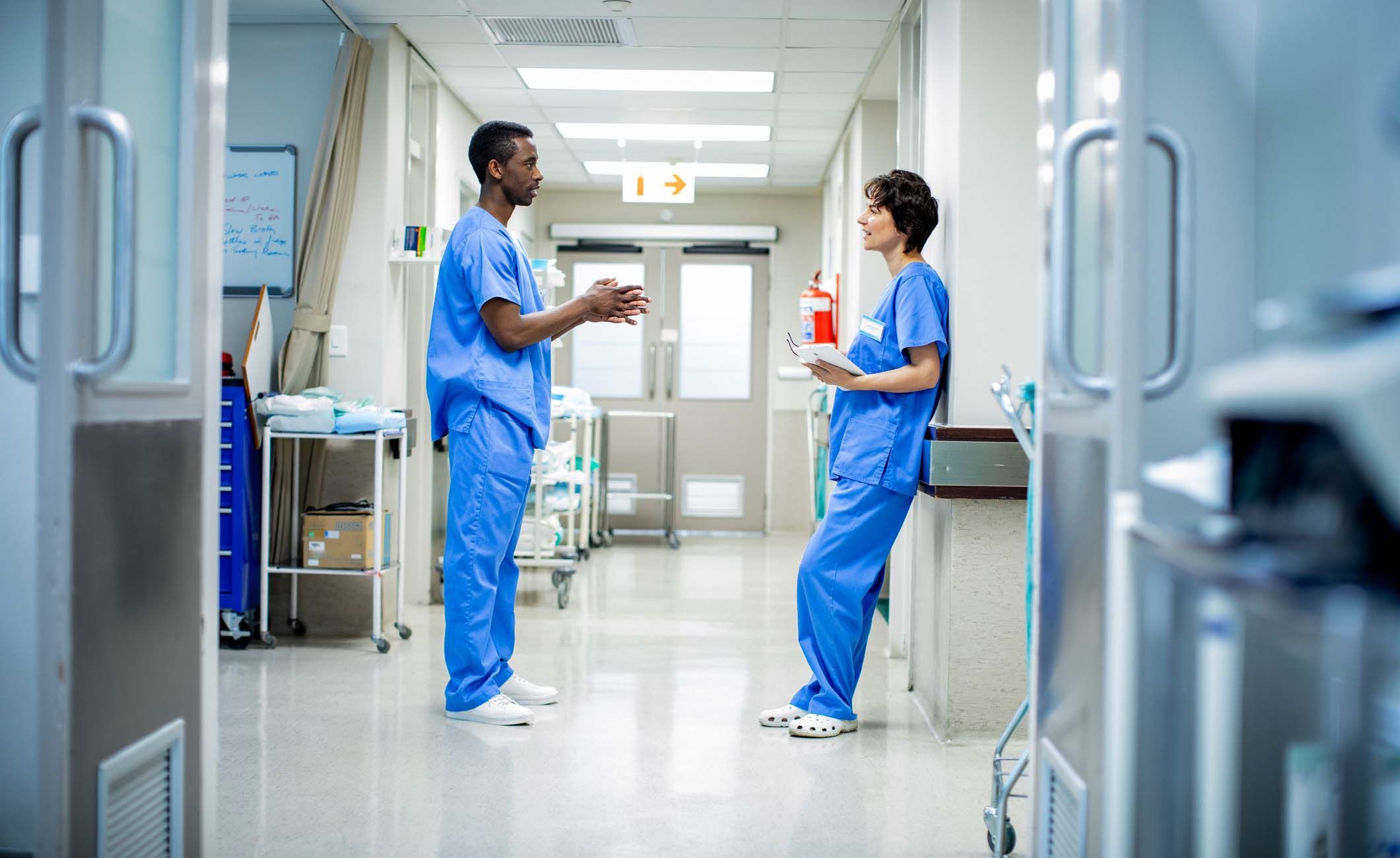 Zwei Krankenpflegehelfer stehen im Krankenhausflur und unterhalten sich