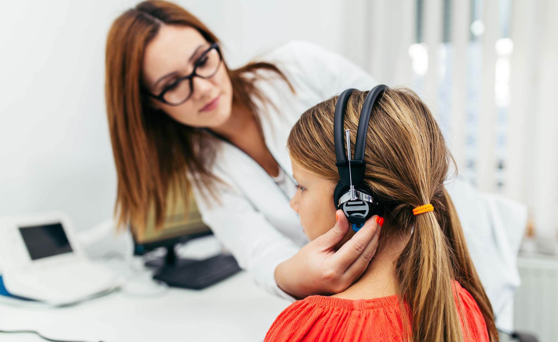 Eine Hörakustikerin macht einen Hörtest bei einem jungen Mädchen
