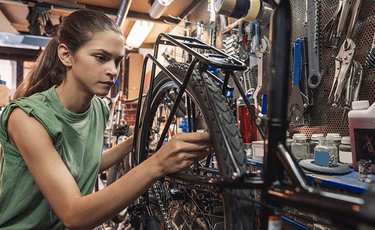 Zweiradmechatronikerin arbeitet an einem Fahrrad.