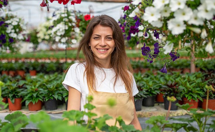 Lächelnde junge Frau steht in einem Blumencenter.