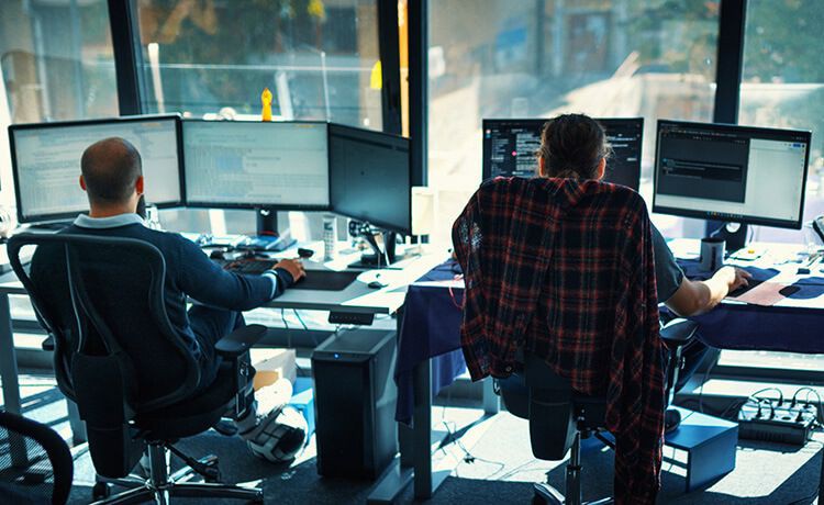 Zwei Programmierer sitzen in einem Büro und programmieren.