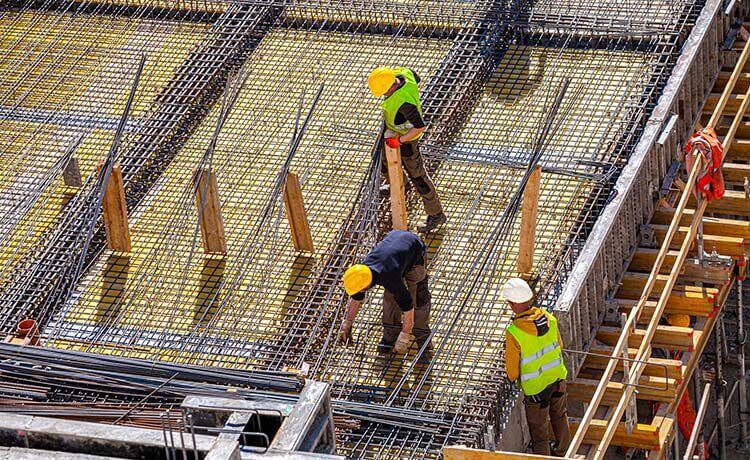 Drei Beton- und Stahlbetonbauer arbeiten auf einer Baustelle.