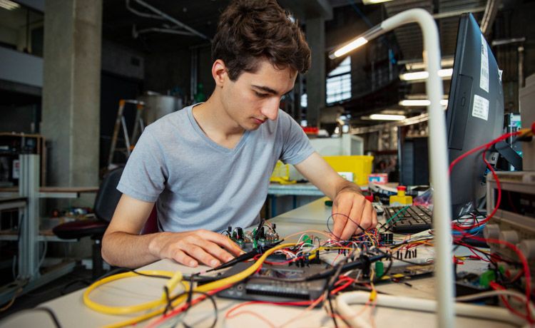 Ein Student im dualen Studium Elektro- und Informationstechnik hantiert mit Stromkabeln.