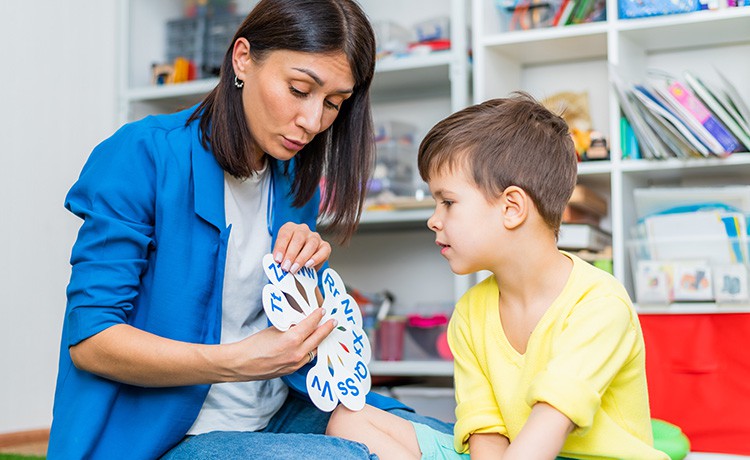 Junge Frau hilft einem kleinen Jungen beim Lesen lernen.