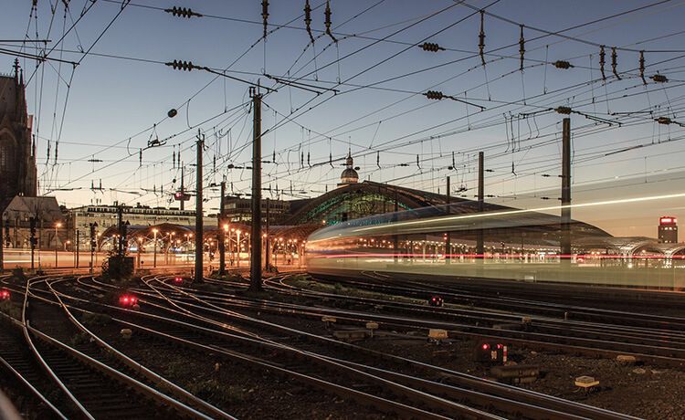 Blick auf Kölner Hauptbahnhof und Schienennetz bei Sonnenuntergang.