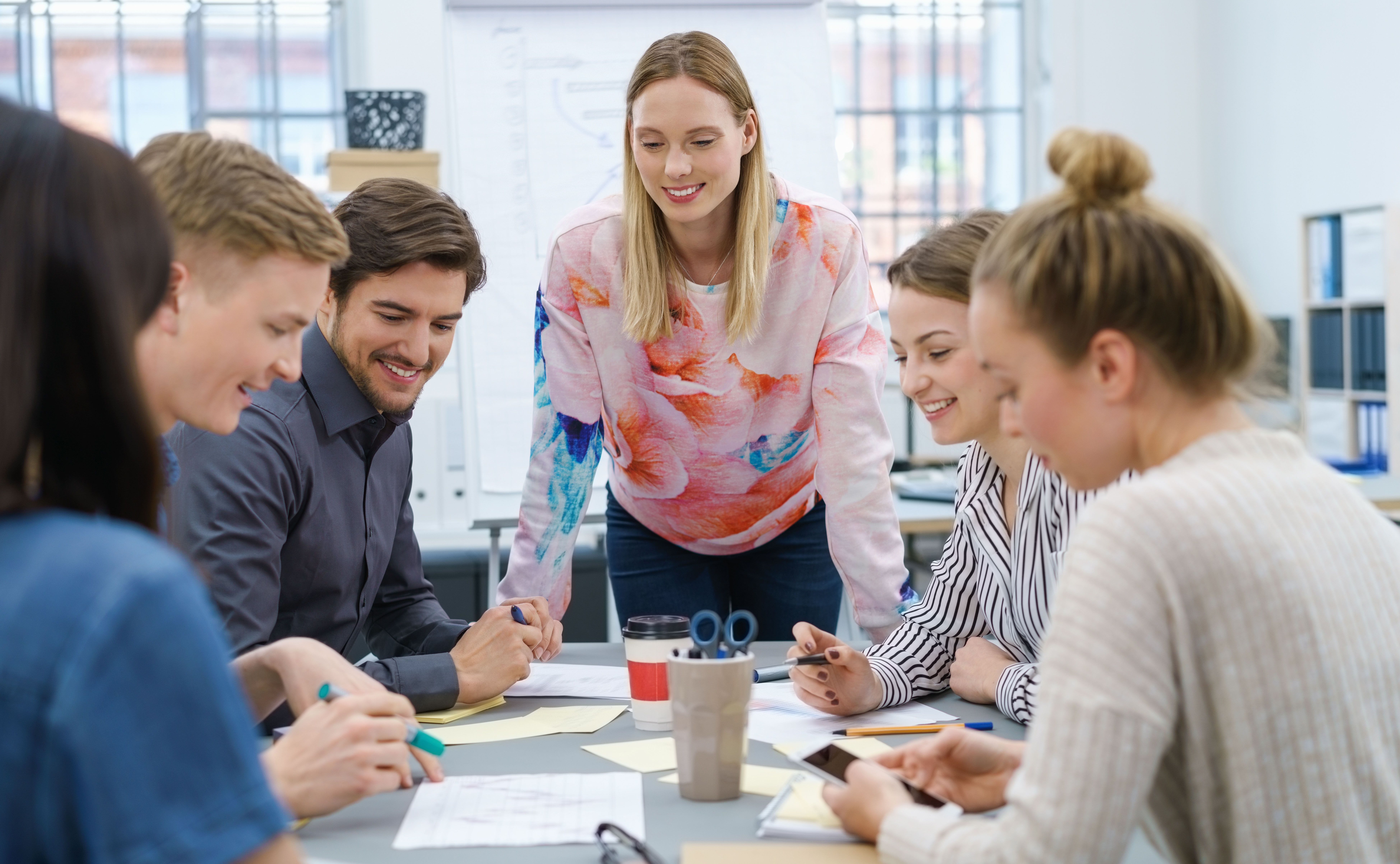 Junge Menschen stehen am Tisch und besprechen gemeinsam Anliegen der jungen Mitarbeitenden der JAV