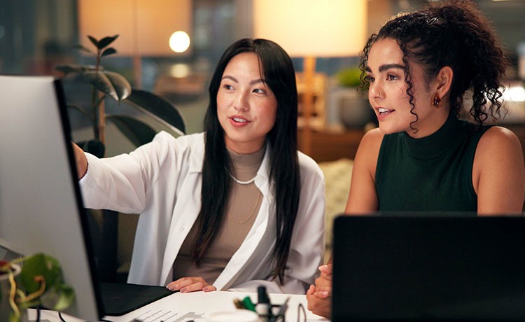 zwei junge Frauen arbeiten gemeinsam an einem PC