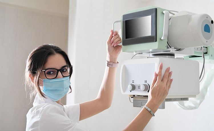 Junge Frau mit Maske stellt ein Gerät im Krankenhaus ein.