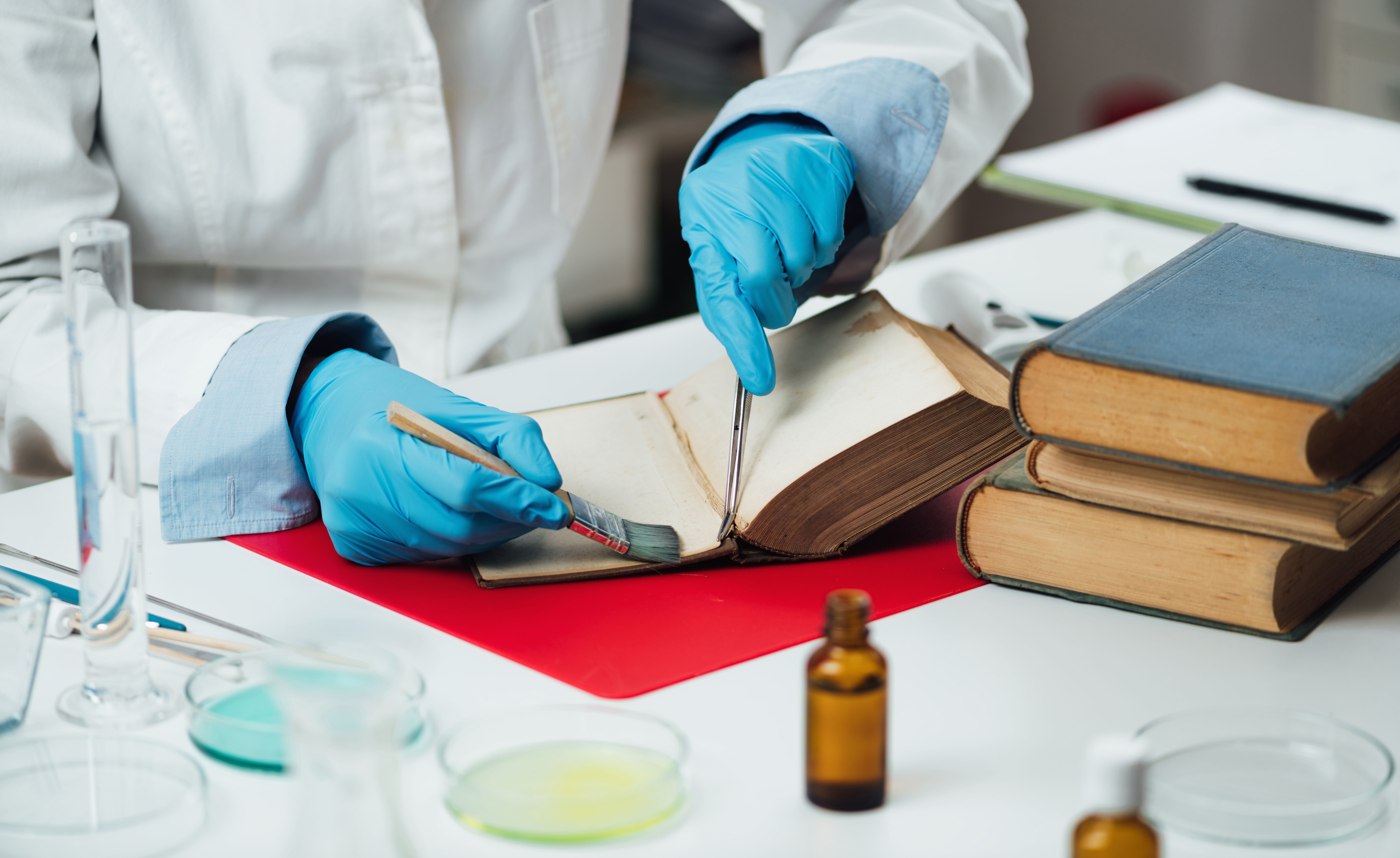 Buchrestaurator repariert beschädigte Seiten in einem antiken Buch.