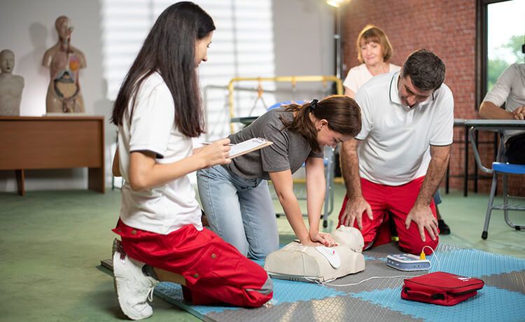 Auszubildende zur Rettungssanitäterin übt bei einem Erste-Hilfe-Kurs eine Herzdruckmassage an einer Übungspuppe.