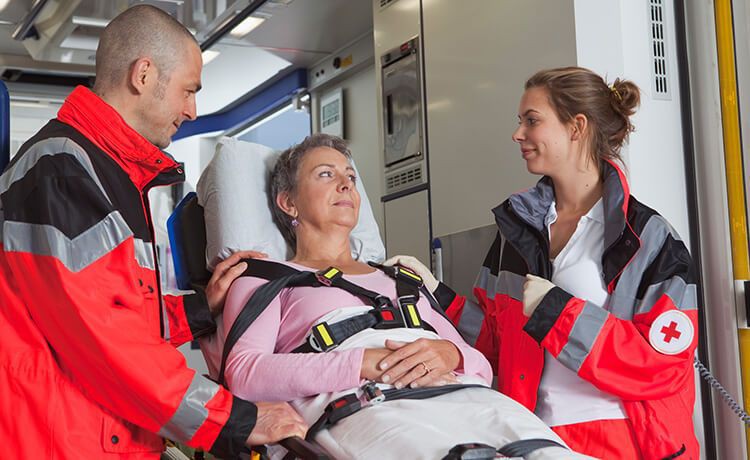 Zwei Rettungssanitäter kümmern sich im Krankenwagen um eine Patientin, die auf einer Trage liegt.