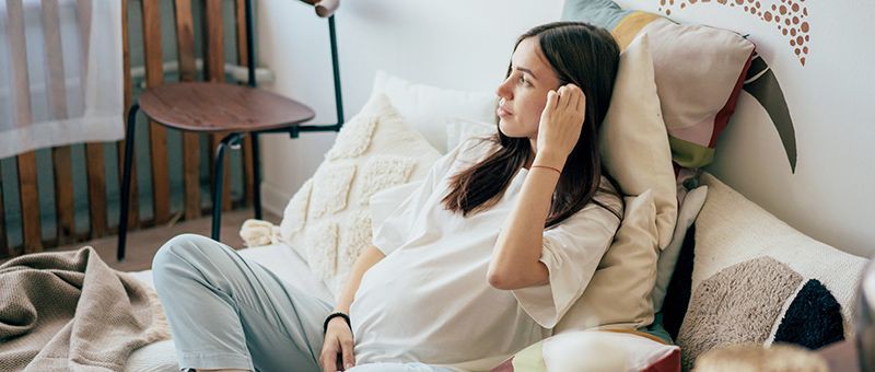 Eine schwangere Auszubildende sitzt im Bett