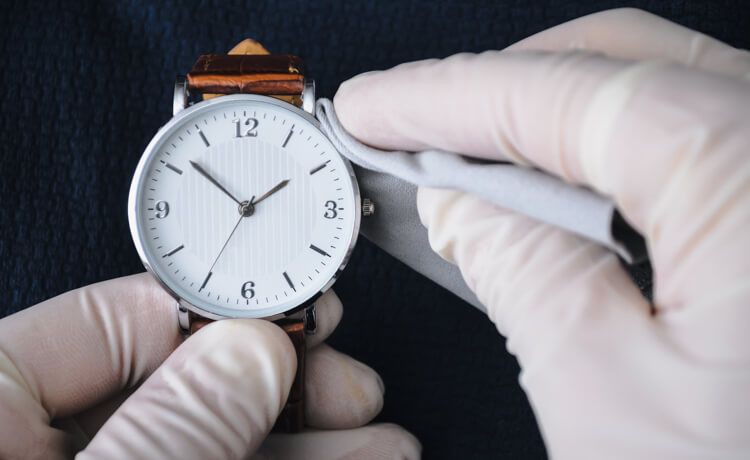 Uhrmacher mit Putztuch und Armbanduhr