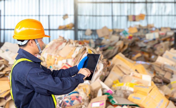 Umwelttechnologe erfasst Daten mit dem iPad auf einem Recyclinghof.