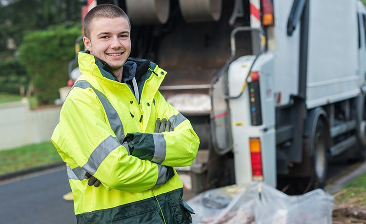 Junger Mann arbeitet bei der Müllabfuhr.